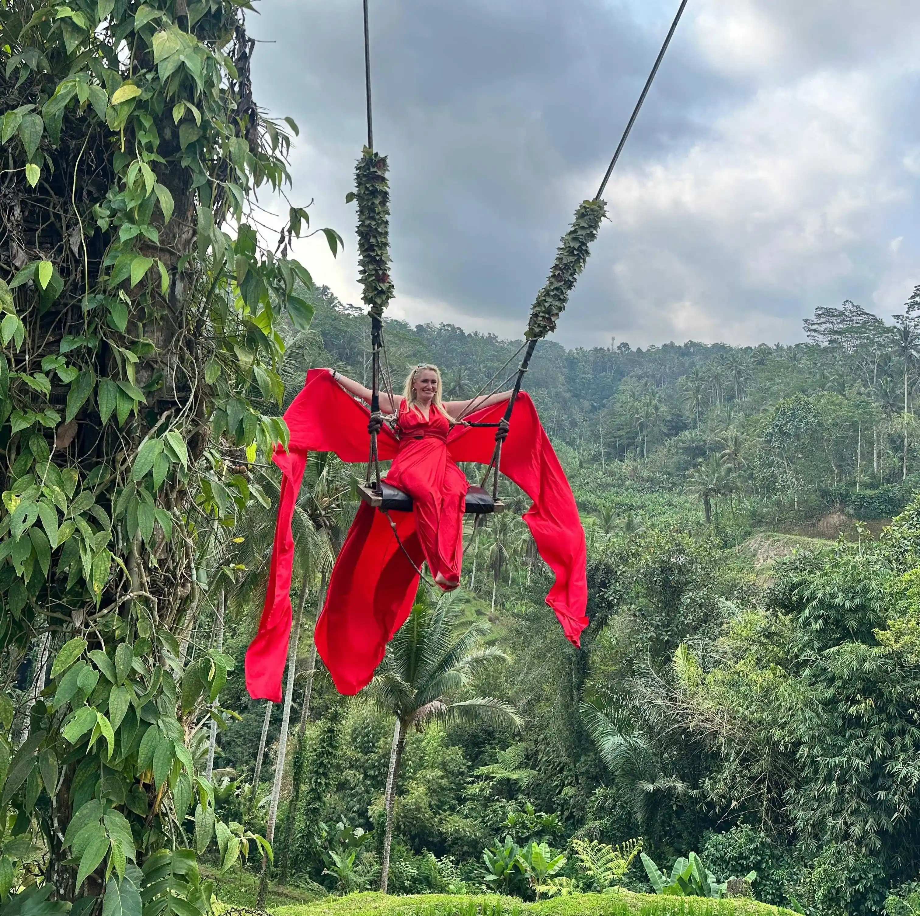 Woman soaring on a giant jungle swing above lush tropical canopy in Bali